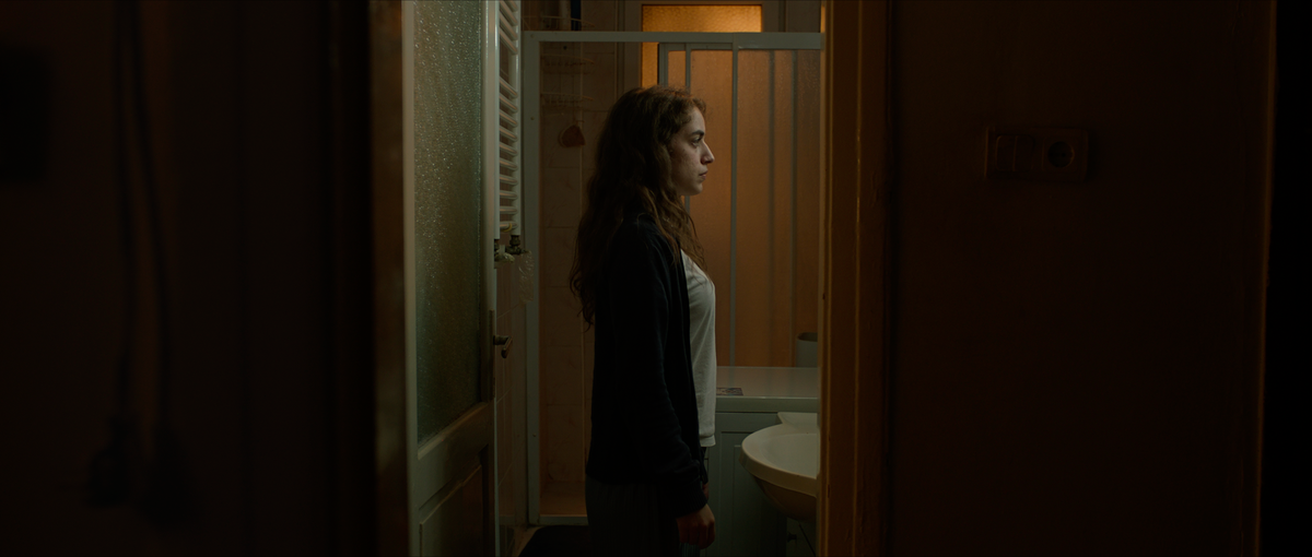 Isolated in her bathroom, Deniz, the film's protagonist, looks into a mirror.