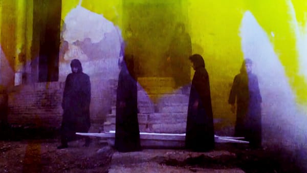 Six figures in headscarves stand around a staircase; the image is discoloured yellow and purple