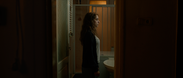 Isolated in her bathroom, Deniz, the film's protagonist, looks into a mirror.